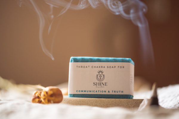 Throat Chakra Soap, wrapped on stone soap dish and cream linen with blurred smoking incense cone and flower buds | Shine Body & Bath