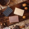 Group of three higher Chakra soaps | Crown Chakra Soap, Third Eye Chakra Soap, Throat Chakra Soap on wooden board with buds and lavender petals, and crystals | Shine Body & Bath