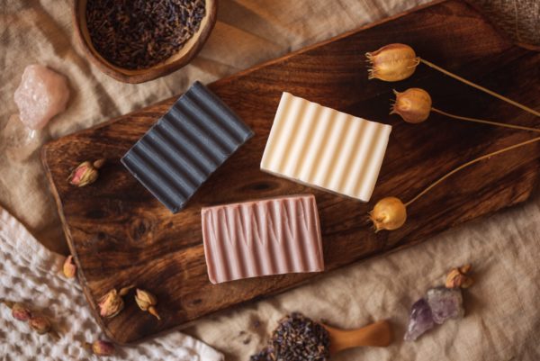 Group of three higher Chakra soaps | Crown Chakra Soap, Third Eye Chakra Soap, Throat Chakra Soap on wooden board with buds and lavender petals, and crystals | Shine Body & Bath