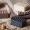 Group of three higher Chakra soaps | Crown Chakra Soap, Third Eye Chakra Soap, Throat Chakra Soap on Cream and lavender coloured towwls and linen with scattered flower buds, and crystals | Shine Body & Bath