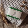 Heart Chakra Soap, wrapped on cream waffle fabric with dried ear of grass and scattered rose buds | Shine Body & Bath