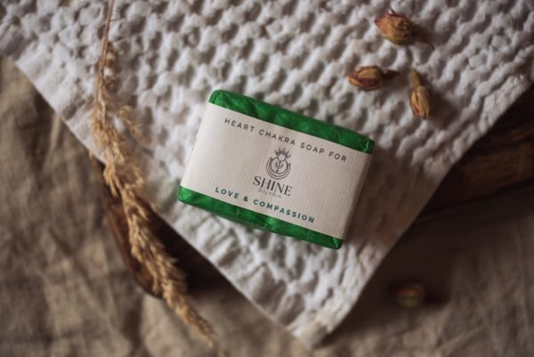 Heart Chakra Soap, wrapped on cream waffle fabric with dried ear of grass and scattered rose buds | Shine Body & Bath