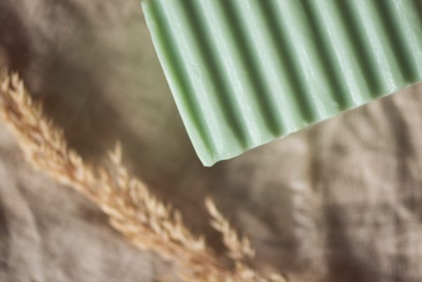 Up close corner of Heart Chakra Soap, unwrapped on cream linen with dried ear of grass | Shine Body & Bath