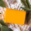 Sacral Chakra Soap, unwrapped on cream waffle fabric with scattered sprigs of green herbs and amethyst crystals | Shine Body & Bath