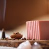 Root Chakra Soap, unwrapped on wooden board with smoking incense cone, scattered dried petals | Shine Body & Bath