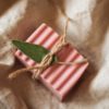 Root Chakra Soap, unwrapped on cream linene fabric, tied with brown string and a green herb leaf | Shine Body & Bath