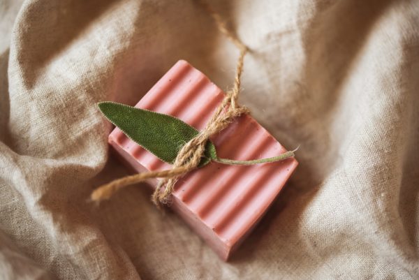 Root Chakra Soap, unwrapped on cream linene fabric, tied with brown string and a green herb leaf | Shine Body & Bath