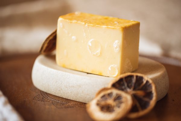 Solar Plexus Chakra Soap, with bubbles sitting on a stone soap dish with dried lemon slices | Shine Body & Bath