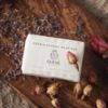 Crown Chakra Soap, wrapped on wooden board with rose buds and scattered lavender petals | Shine Body & Bath