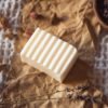 Crown Chakra Soap, unwrapped on crumpled brown paper with scattered rose buds, lavender petals and rose quartz | Shine Body & Bath