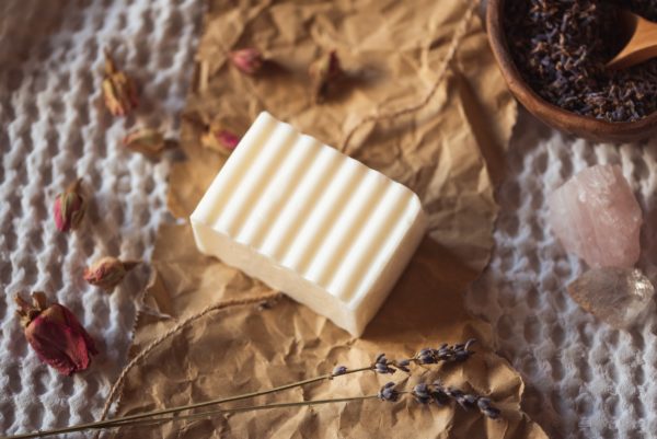 Crown Chakra Soap, unwrapped on crumpled brown paper with scattered rose buds, lavender petals and rose quartz | Shine Body & Bath