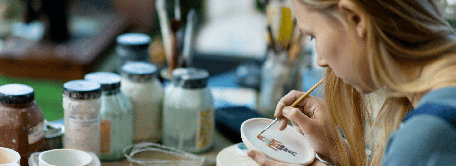 Woman concentrating on painting a piece of pottery | Am I Creative | Shine Body & Bath Chakra Soap | Blog