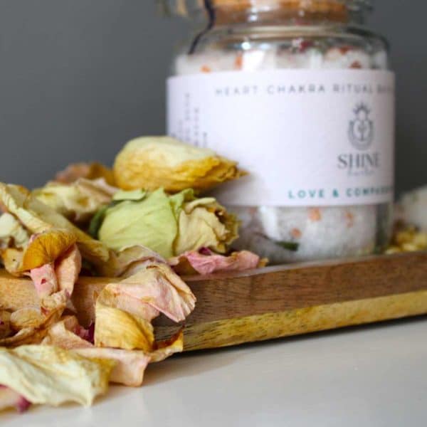 Heart Chakra Ritual Bath Salts for Love & Compassion | Glass jar of bath salts on shelf with rose petals in foreground | Shine Body & Bath