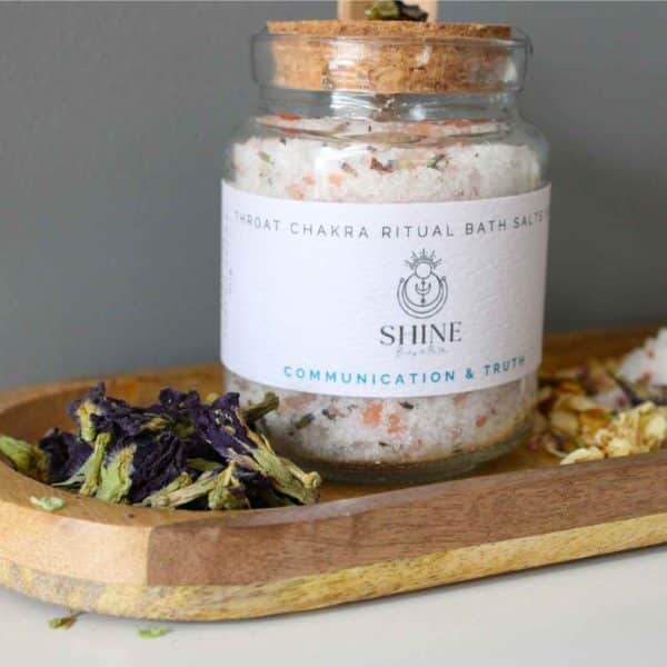 Throat Chakra Ritual Bath Salts for Communication & Truth | Glass jar of bath salts on shelf with blue petals | Shine Body & Bath
