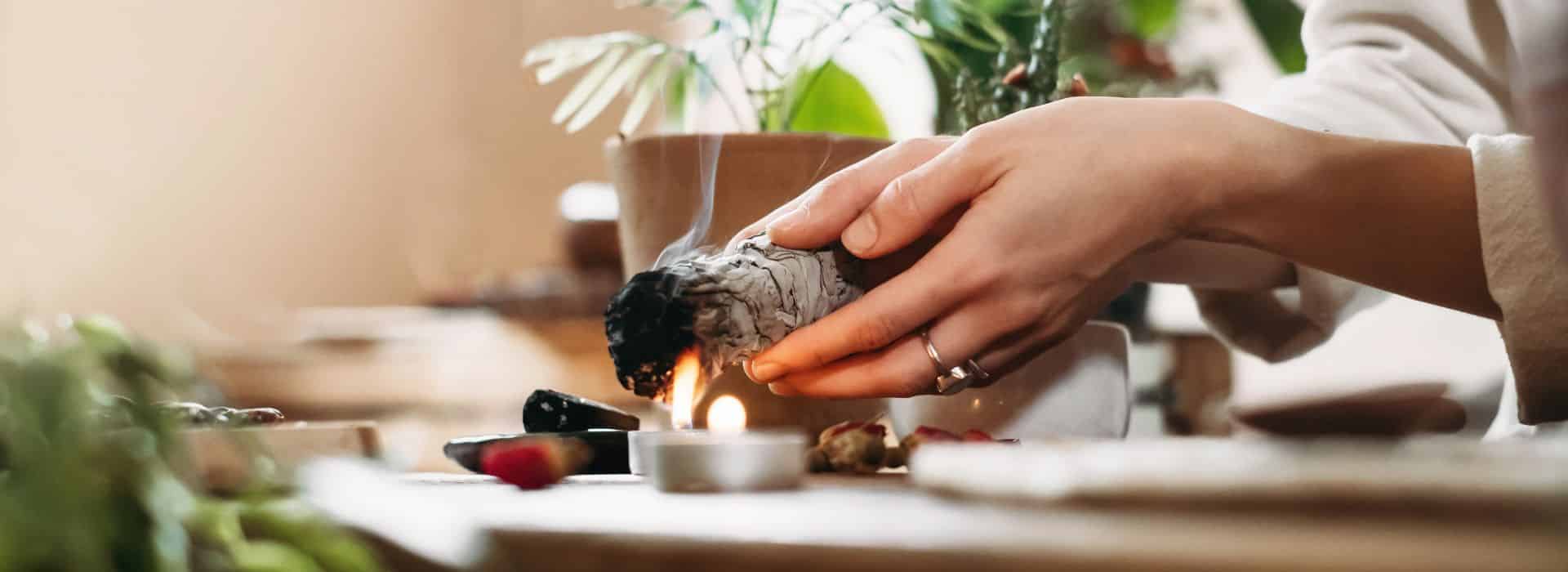 Woman lighting white sage in a cleansing ritual | The Perfect Bath: Create the Ultimate Ritual Bathing Experience | Shine Body & Bath Blog