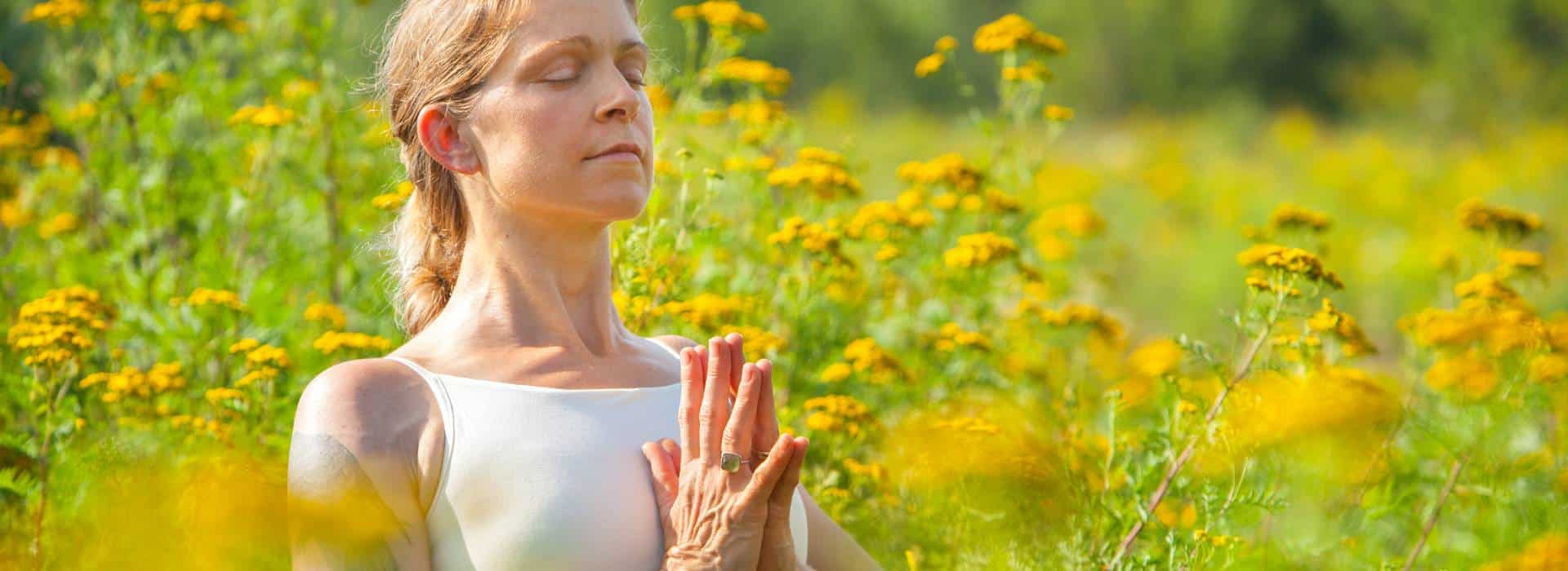 Woman meditating in field of yellow flowers | Activate your Solar Plexus Chakra Fire! | Shine Body & Bath Chakra Soap | Blog