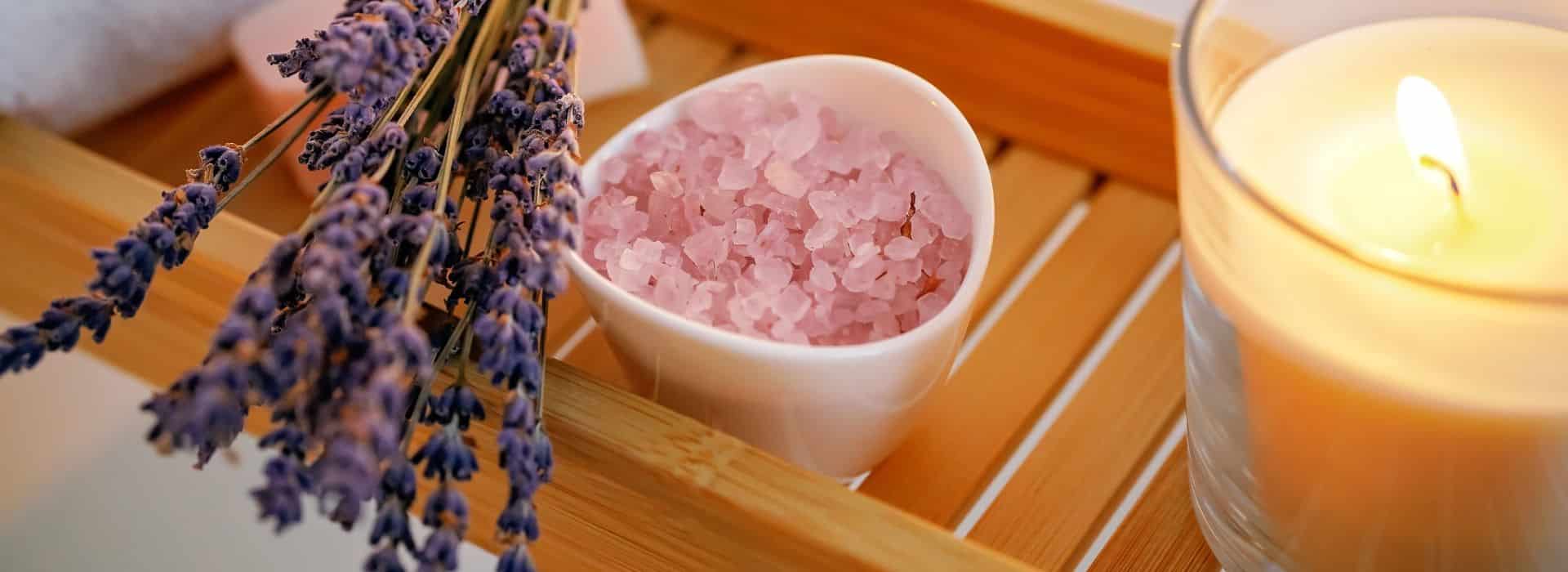 Lavender, pink salt and a lit candle on a bath tray | The Perfect Bath: Create the Ultimate Ritual Bathing Experience | Shine Body & Bath Blog