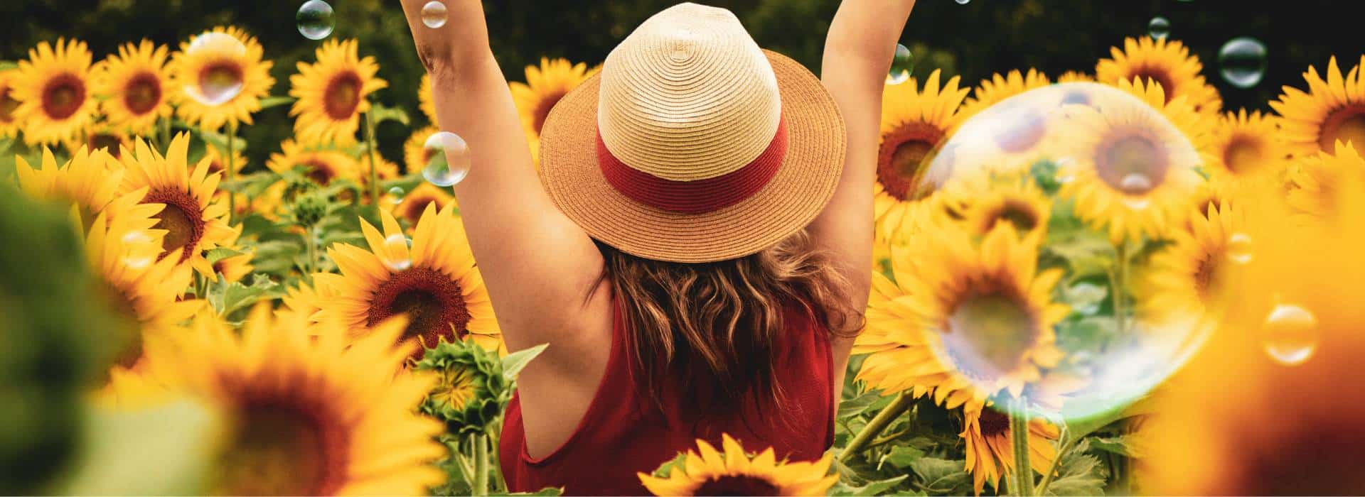 Woman with arms raised standing in a field of sunflowers | Activate your Solar Plexus Chakra Fire! | Shine Body & Bath Chakra Soap | Blog