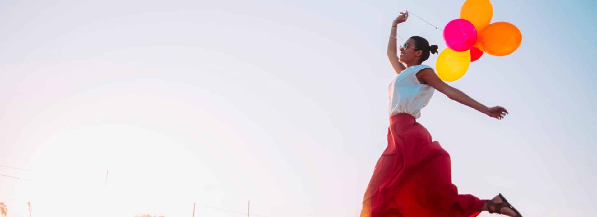 Woman jumping with bunch of balloons | How to live more joyfully | Shine Body & Bath Chakra Soap | Blog