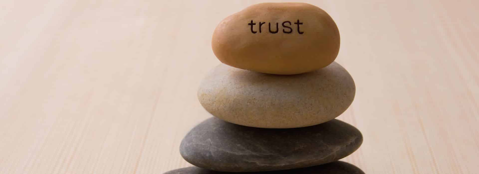 Pile of pebbles with trust written on the top one | How to live more joyfully | Shine Body & Bath Chakra Soap | Blog