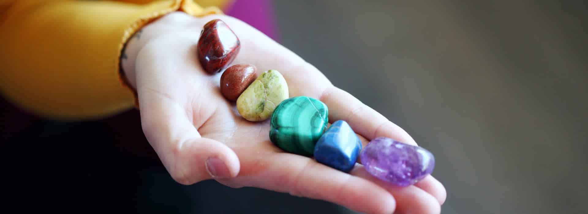 The Chakra System for Beginners - Your Complete Guide | a hand holding chakra crystals