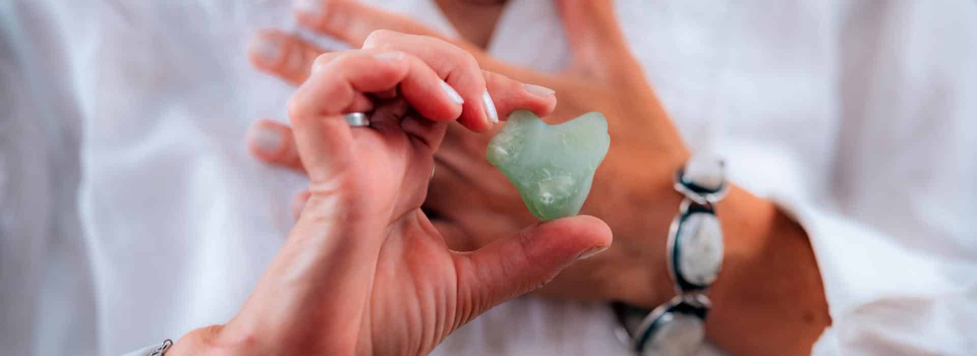 Essential Oils for Chakra Healing: Simple Scents to Balance Your Energy Blog | Woman holding heart shaped jade crystal in front of her chest